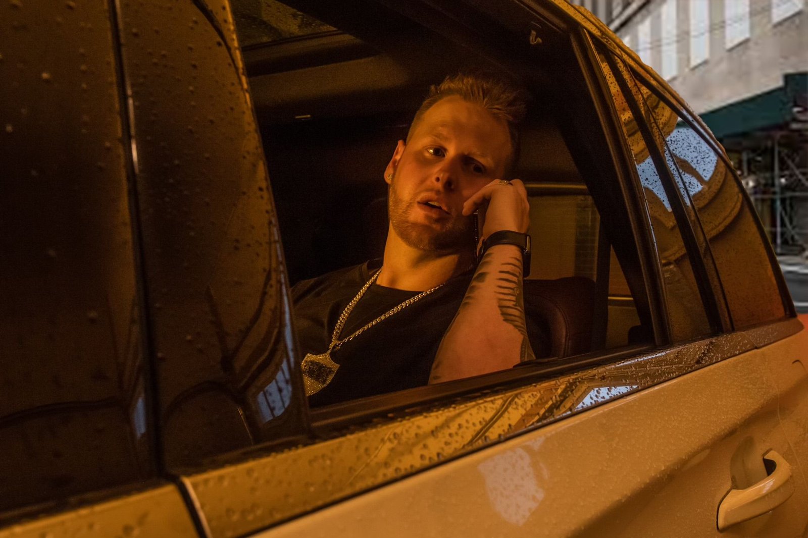 Sean Frost on the phone in the back of a rain-speckled car