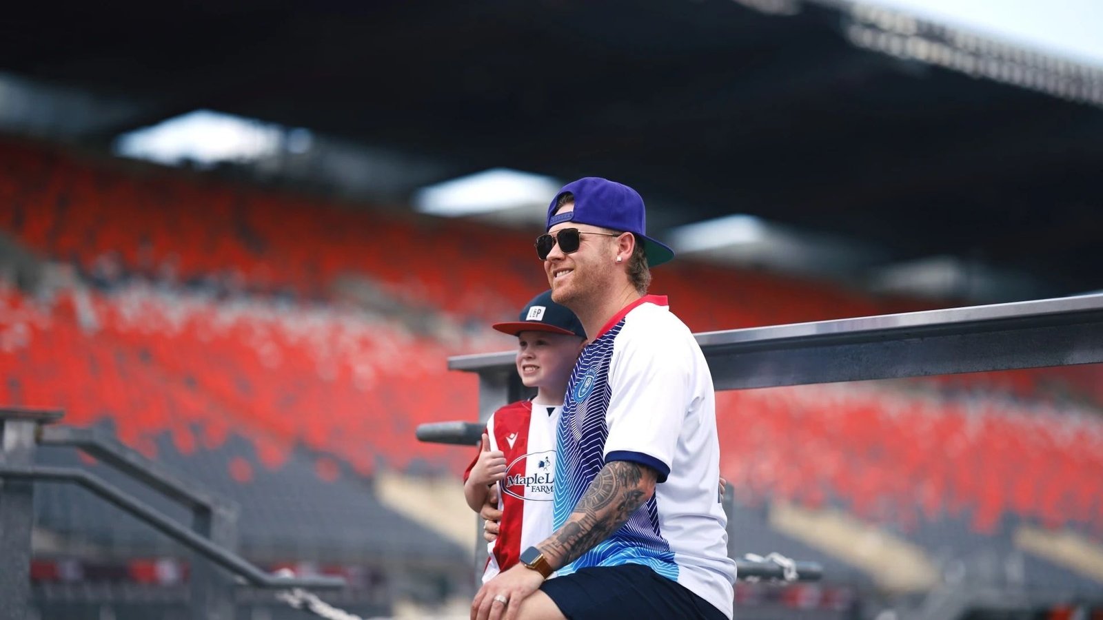 Sean Frost smiling beside a young fan in the stadium stands