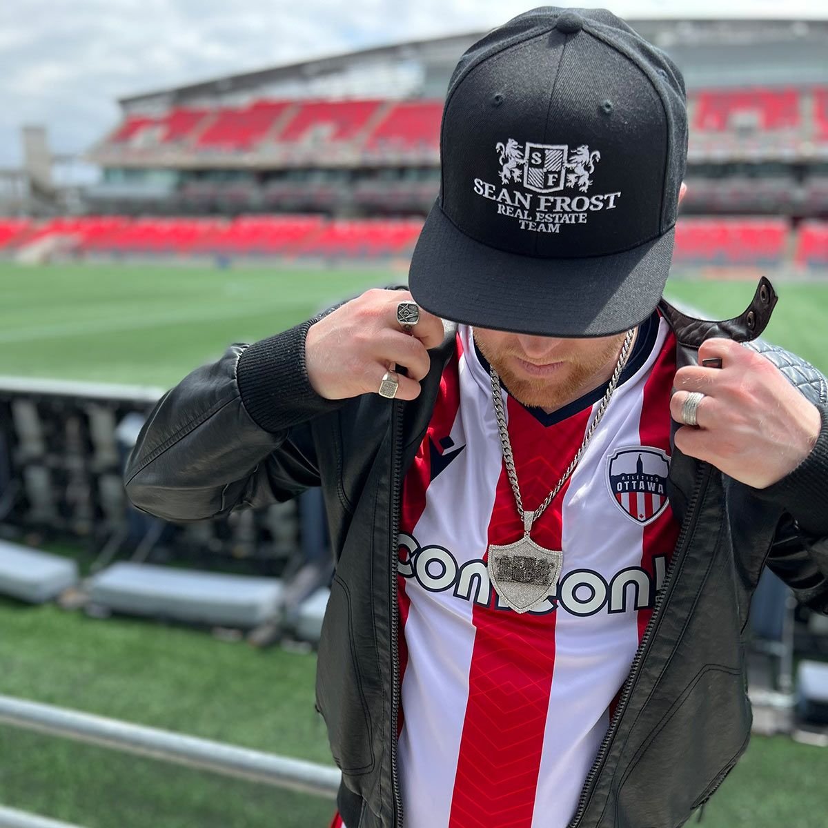Sean Frost adjusting a leather jacket over his jersey pitch-side