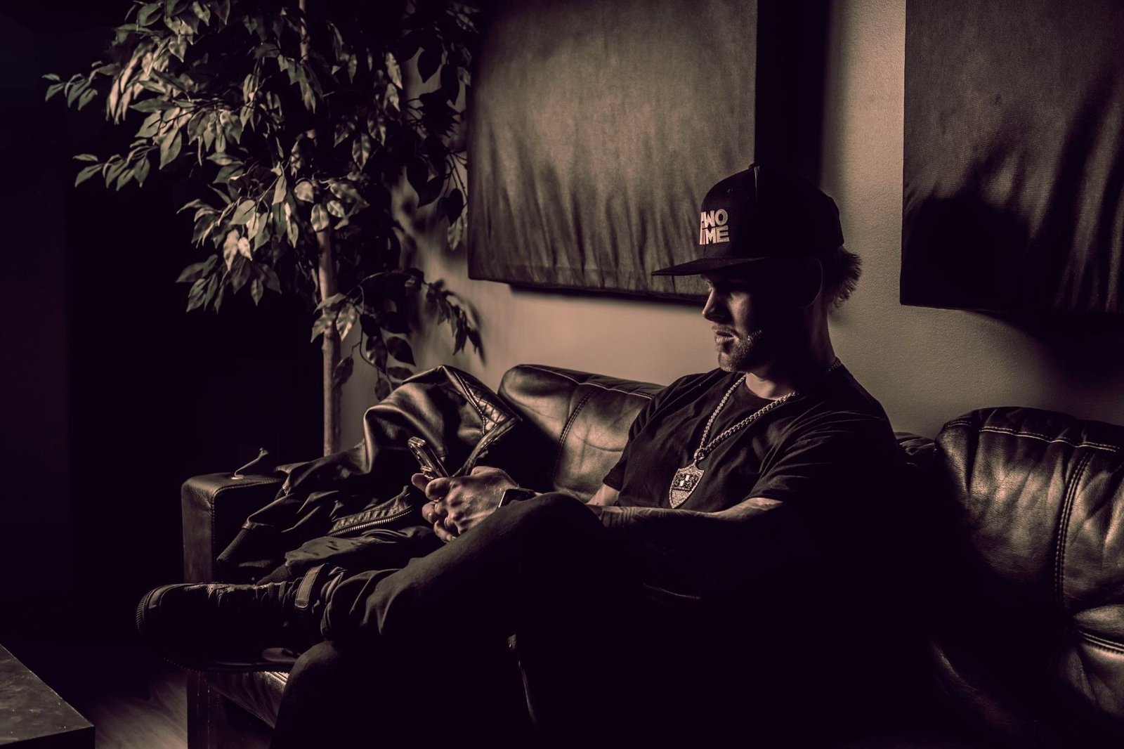 Sean Frost on a leather studio couch checking his phone