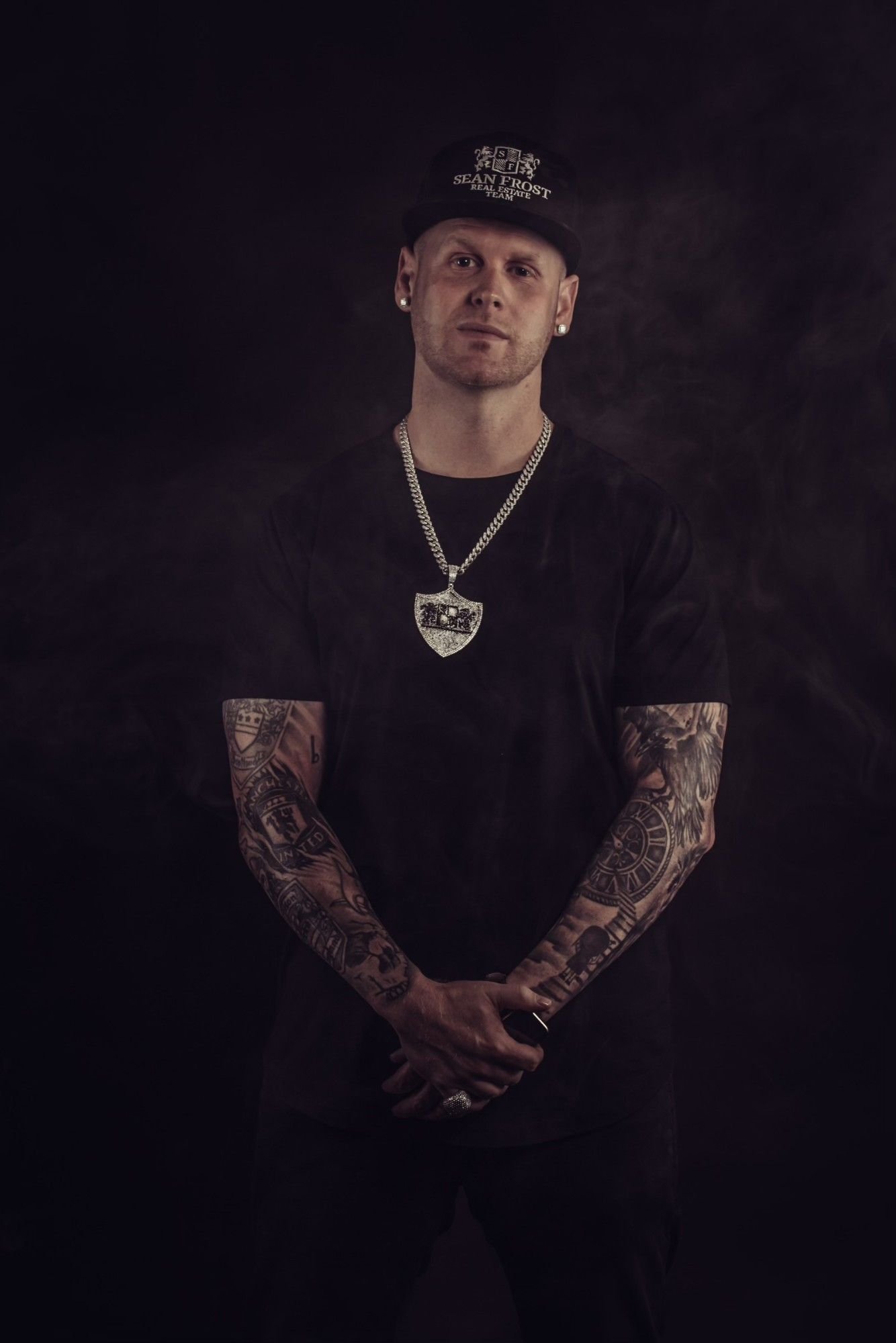 Studio portrait of Sean Frost with hands clasped in front of smoke
