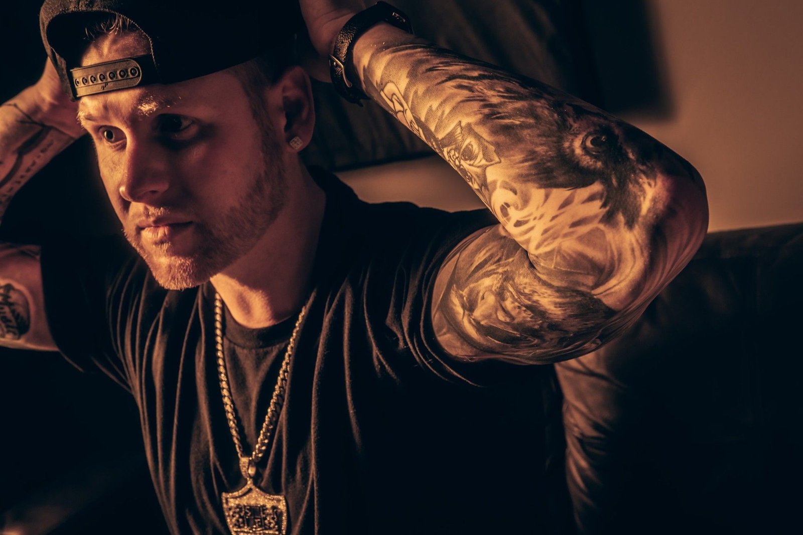 Sean Frost in a backwards cap, his tattooed sleeve lit in amber